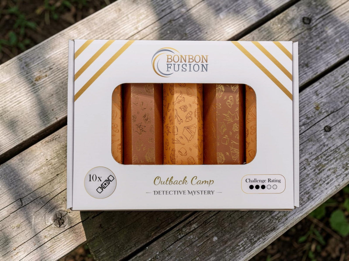 Close-up of the Bonbon Fusion Outback Camp Detective Mystery box of ten orange and gold Christmas bonbons with a challenge rating of 3 out of 5, on a wooden picnic table