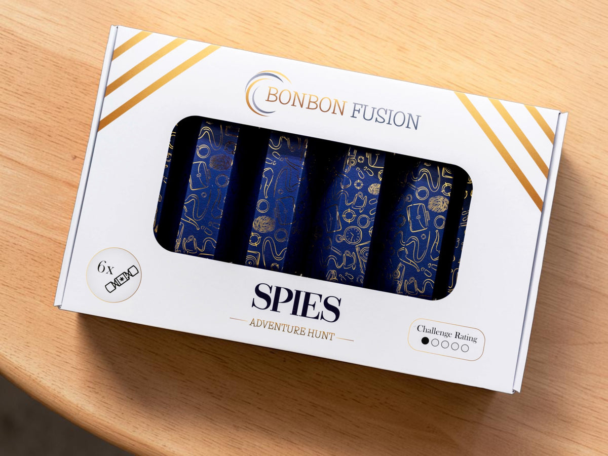 Bonbon Fusion Spies Adventure Hunt pack of six navy and gold spy-themed Christmas bonbons in a white gift box on a wooden table