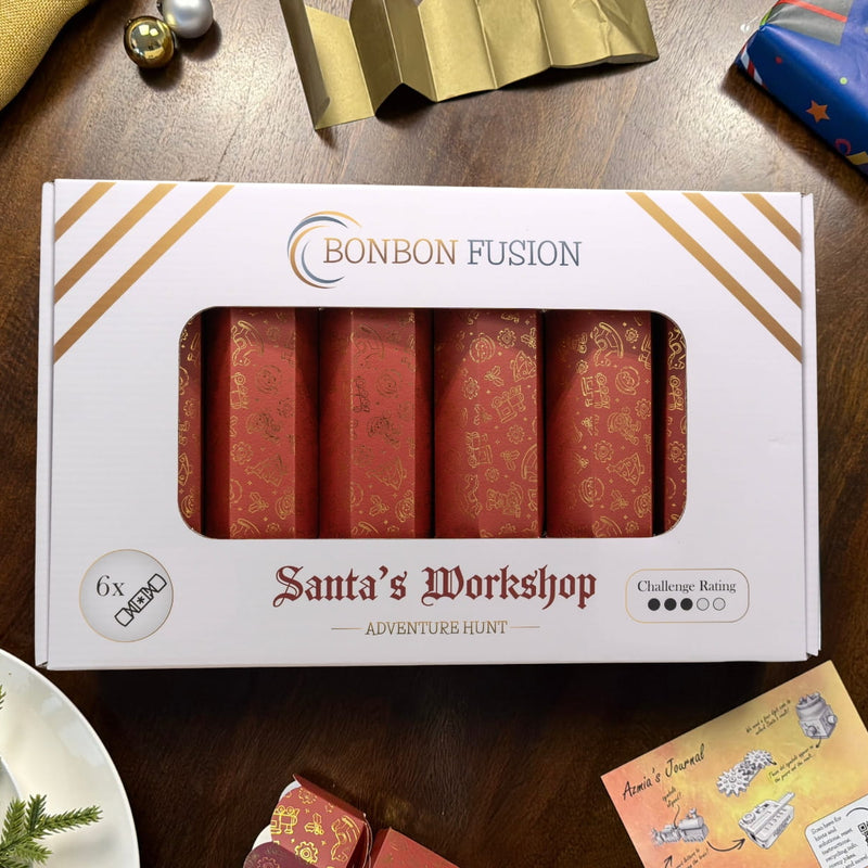 Bonbon Fusion Santa’s Workshop Adventure Hunt pack of six red and gold Christmas bonbons on a wooden table, surrounded by wrapped gifts, festive tableware, a gold paper crown and Azmia’s journal card.
